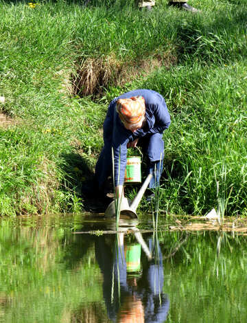Mujer recoge el agua del lago №26577