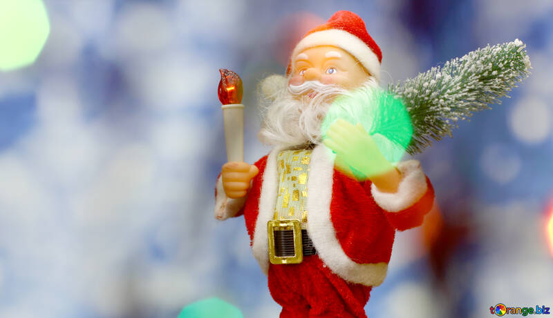 Santa Claus toy brings Christmas tree at blue snowy night bokeh background and blurred lights foreground. Red lantern torch to light the way. Big Copyspace concept New Year`s market banner, poster. №48160