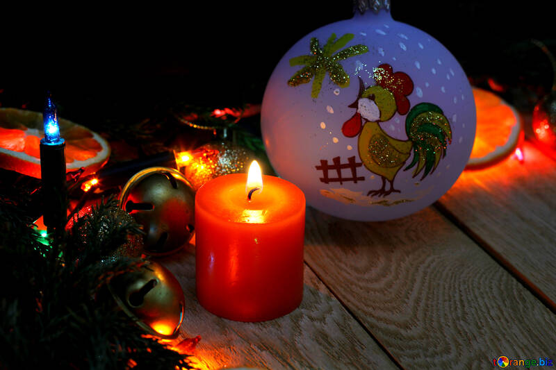 Weihnachtskerze und Kugelhahn mit einem Symbol des Jahres auf einem hölzernen Hintergrund №48189