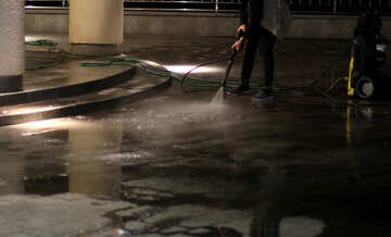 A person washing a street with a hose №49360