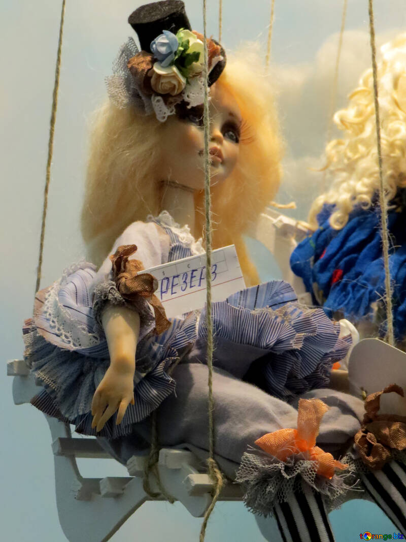 Une poupée fantaisie avec des cheveux blonds bouffis assis sur une balançoire №49067