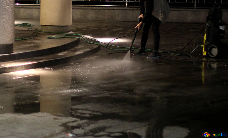 A person washing a street with a hose №49360
