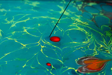 赤い点を有する液体のプール、および棒によって青色の液体に引き込まれるように見える光沢のある緑色のパターン。 №50906