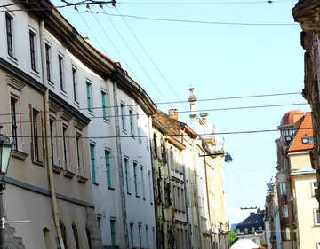 Buildings on a street with a clear blue sky and phone lines visible beautiful building street houses №51945