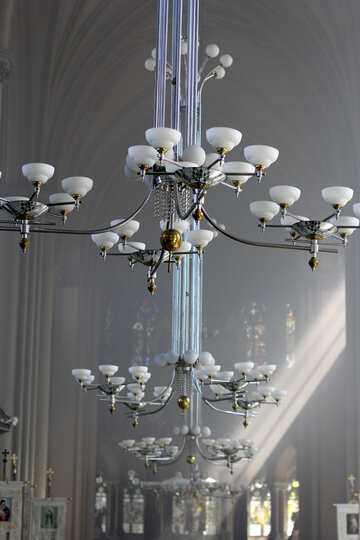 Verzierte Beleuchtungshilfen hängen in einer Halle mit Sonnenlicht №51678