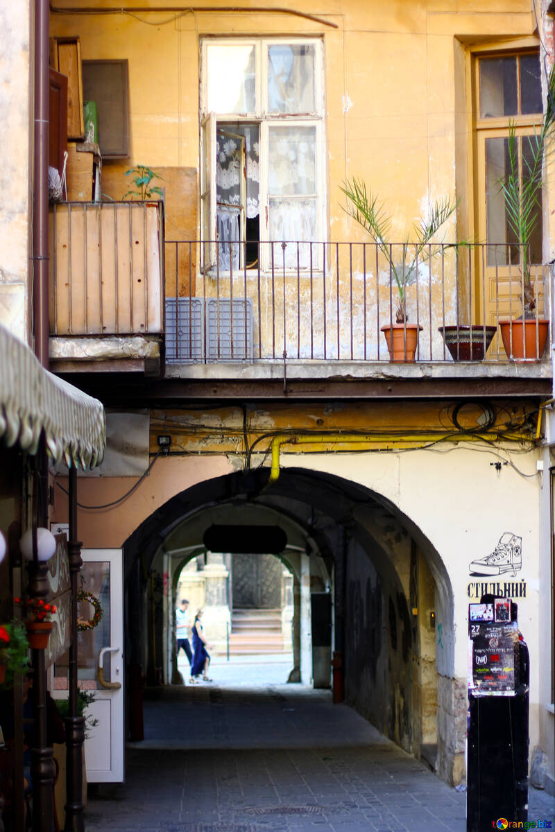 Eingang eines Hauses mit einem Torbogen und einer Palme auf einem Topf und einem Balkon №51887