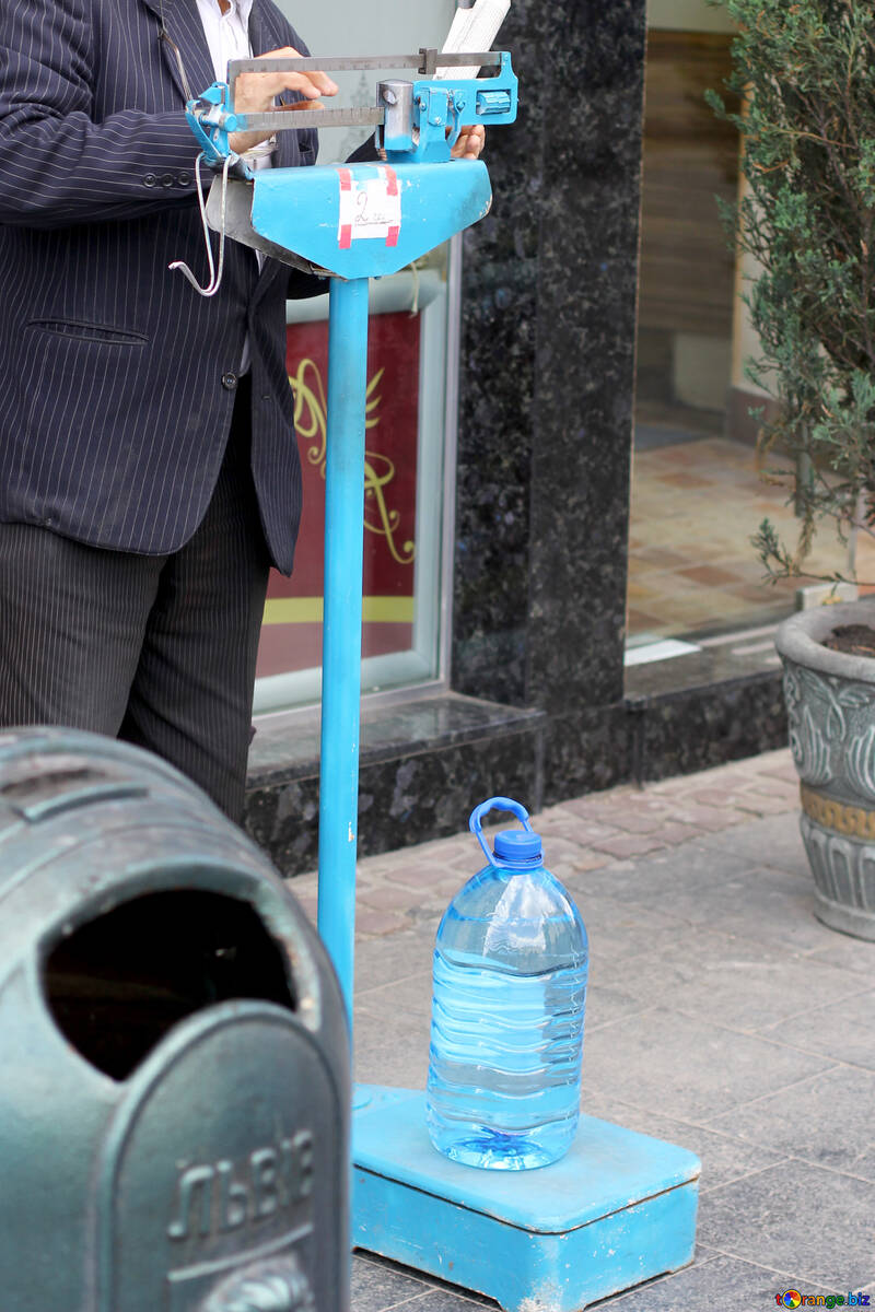 Un monsieur qui règle une balance bleue où il y a une bouteille d`eau №51811