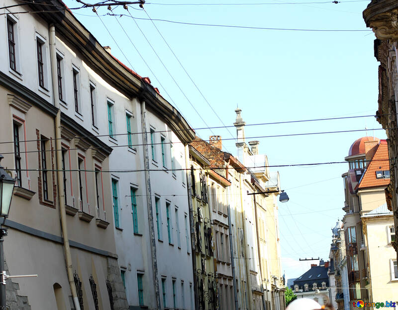 Edifícios em uma rua com um céu azul claro e linhas de telefone visível belo edifício rua casas №51945