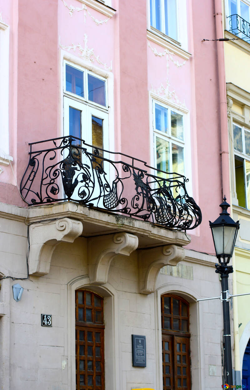 Un edificio con una puerta y un balcón con ventanas. Casa blanca rosada. №51919