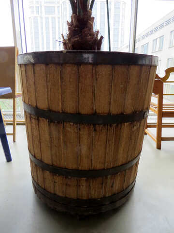 Un barril marrón sentado en el suelo con sillas en el fondo. №52356