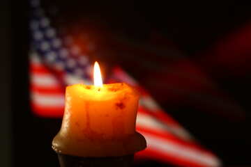 Una vela con una llama frente a una bandera estadounidense. №52487