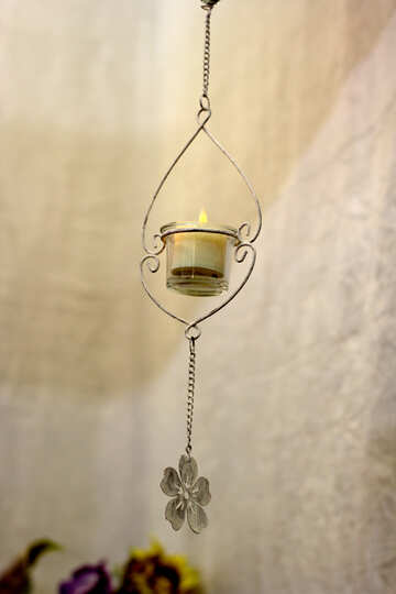 a candle hanging from a wall with a flower chain hanging below Candle lantern wire hearts with Hanging container №52820