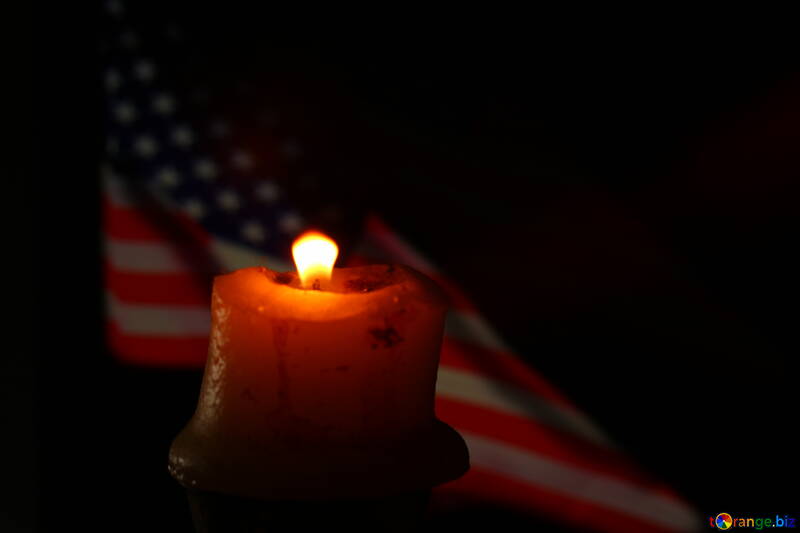 Uma vela acesa e uma bandeira americana ao fundo №52483