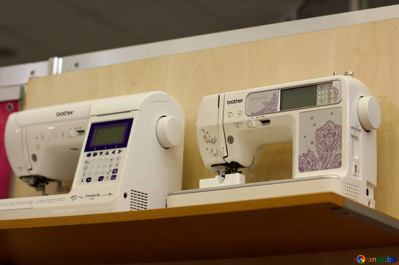 Dos máquinas de coser blancas sobre una superficie de madera con un fondo marrón №52572