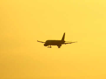 Ein großer Passagierjet, der durch einen Sonnenuntergangskämpfer des bewölkten Himmels fliegt №53464