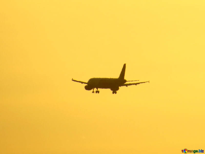 Ein großer Passagierjet, der durch einen Sonnenuntergangskämpfer des bewölkten Himmels fliegt №53464