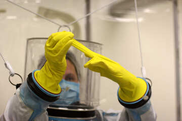 Жінка із захисним костюмом розмовляє рукавицею з лікарських рукавичок Biohazard Yellow №54628