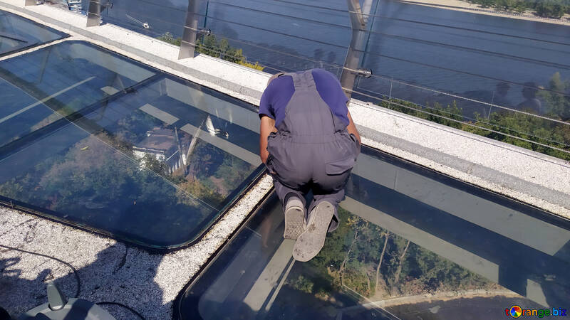 Um homem trabalhando em um trabalhador de telhado de vidro consertando ponte de vidro №55906