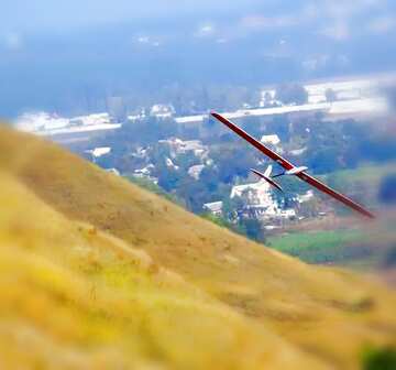 FX №22171 A glider flying over a yellow hill