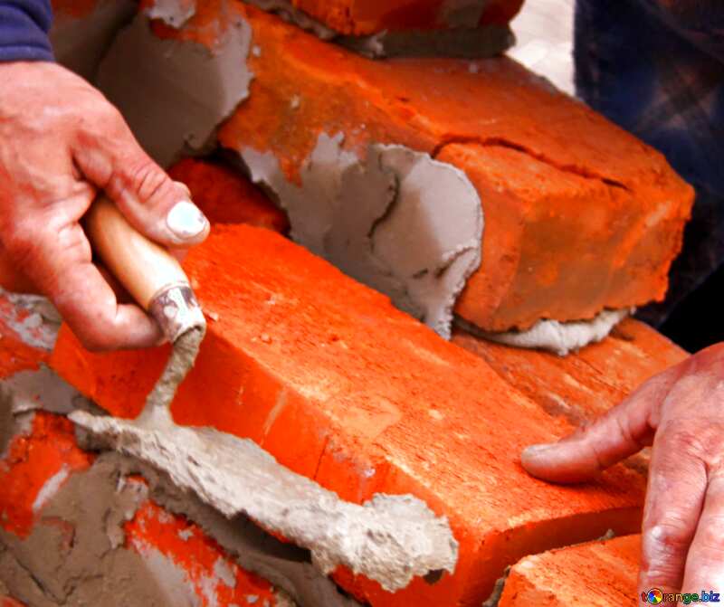 the construction worker lubricates mortar on a trowel on the brick №2891